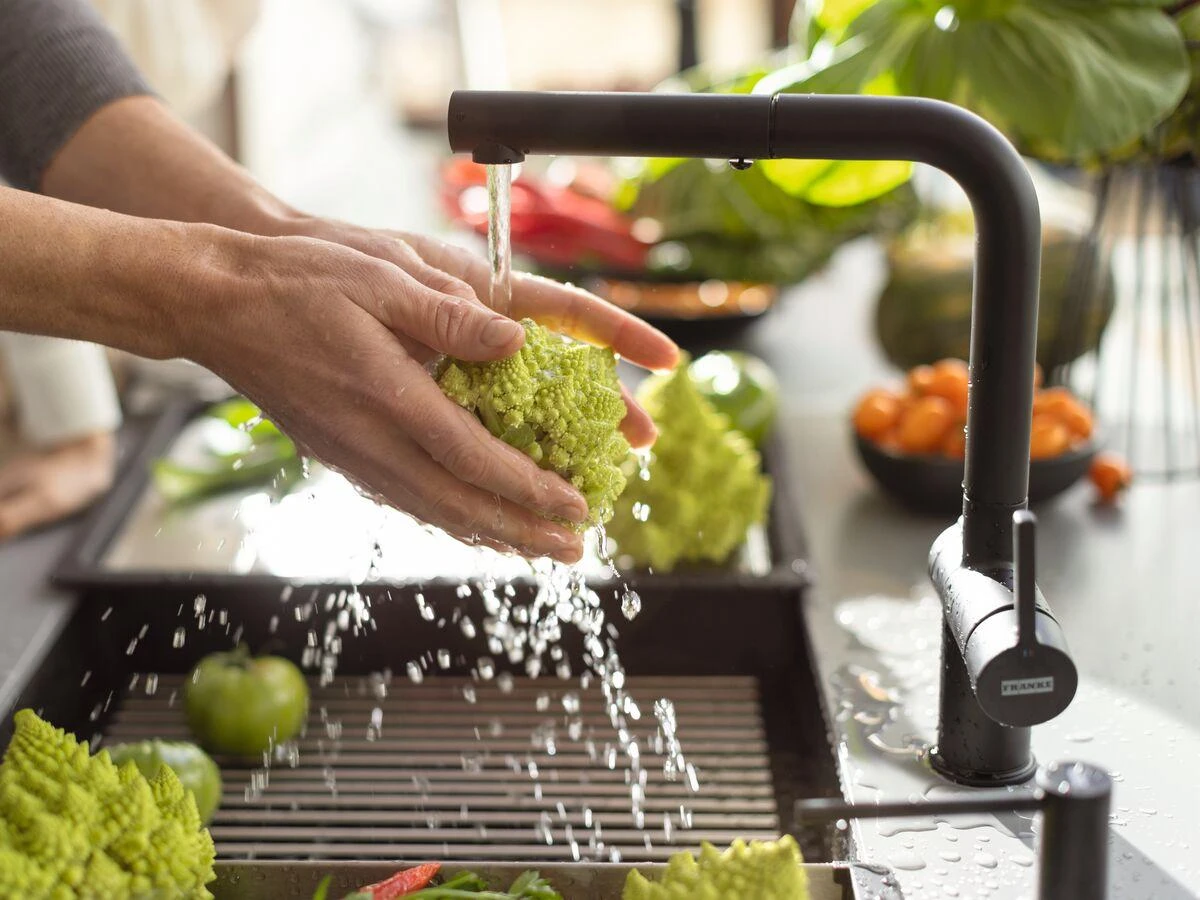 Hands washing fresh vegetables at a kitchen sink in a modern Australian home